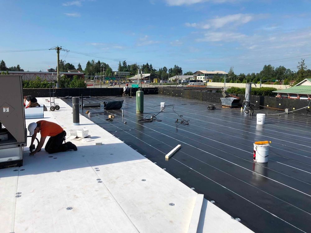 A man is kneeling on the roof of a building.