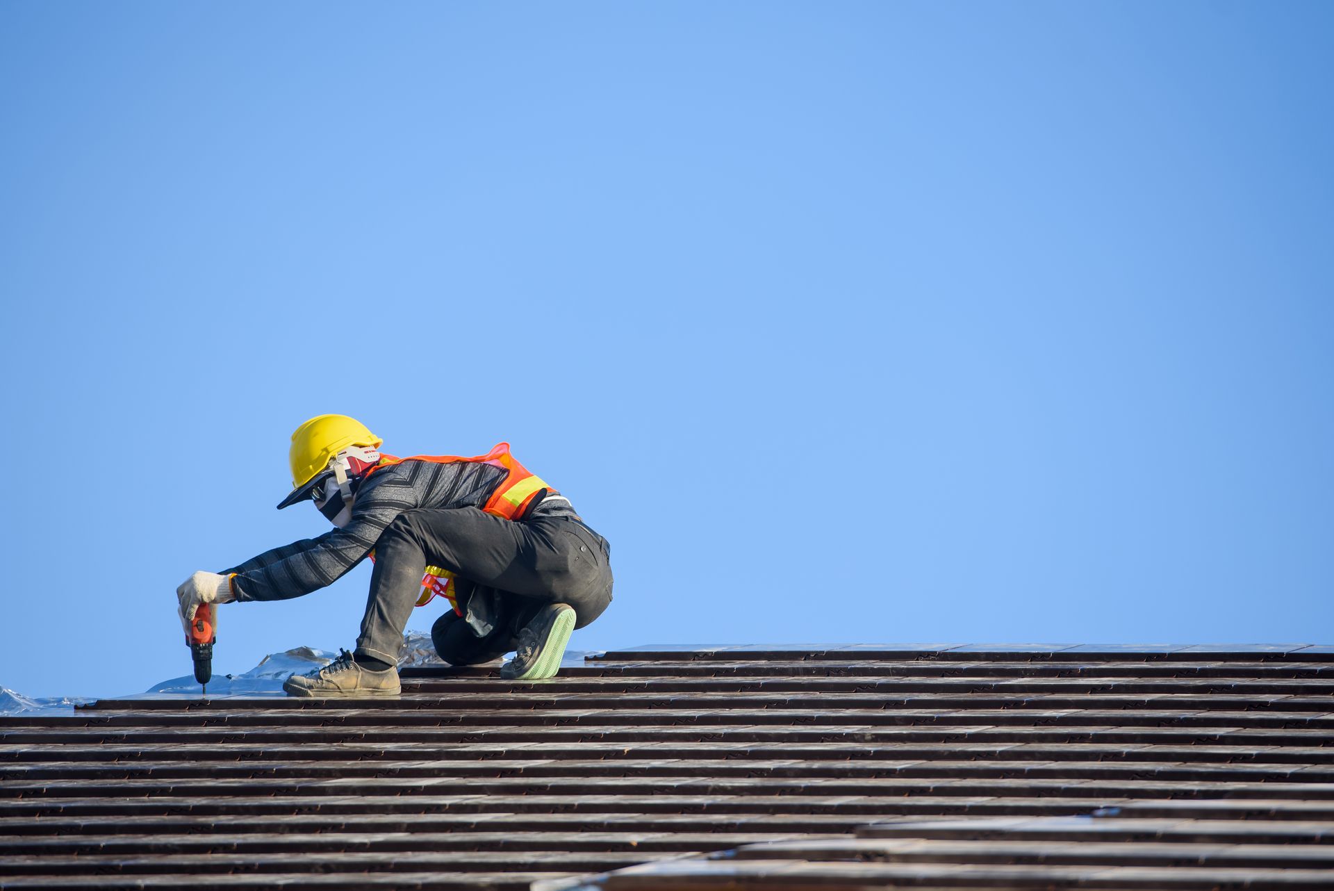 A man is working on a roof with a drill.