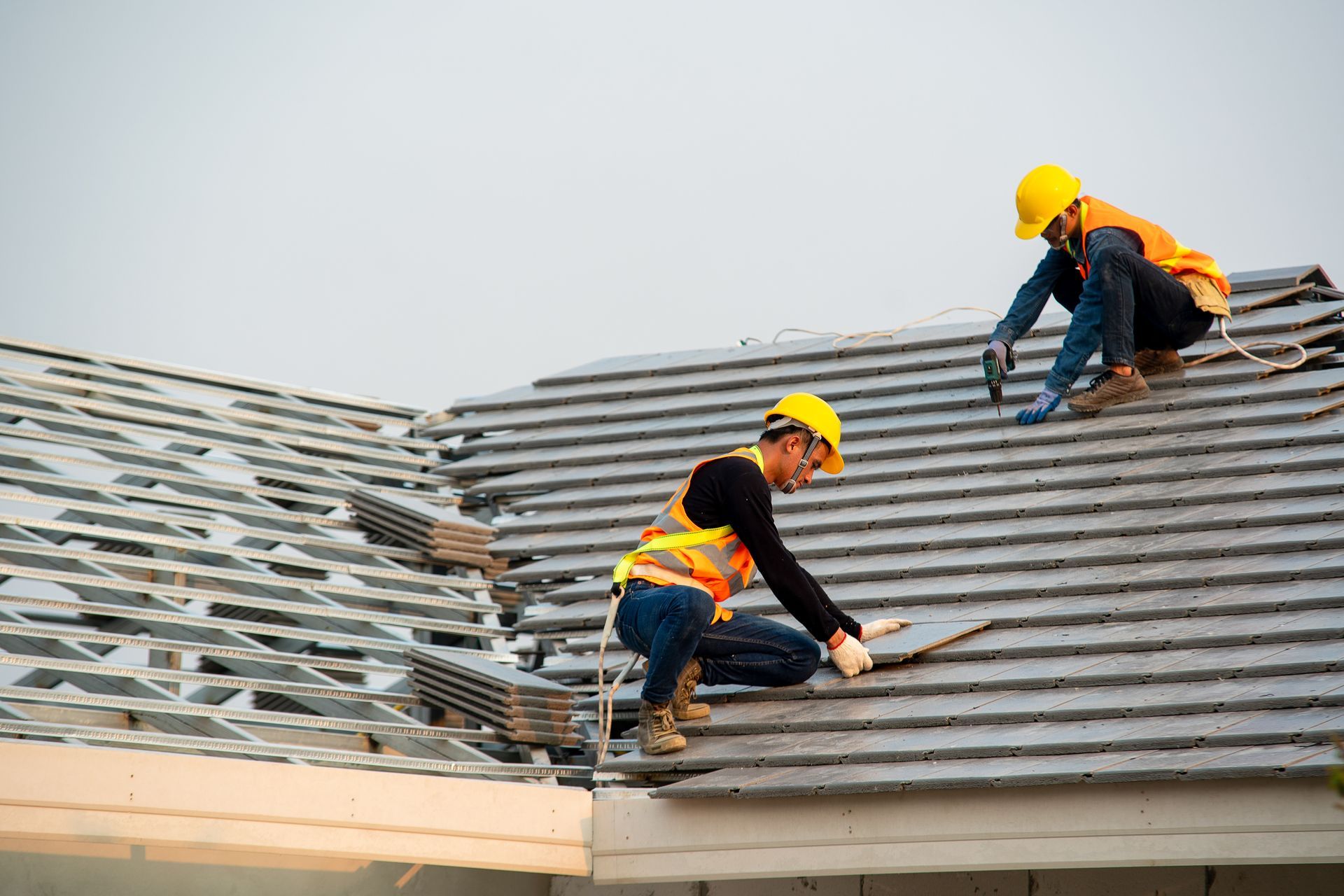 Two construction workers are working on the roof of a house.