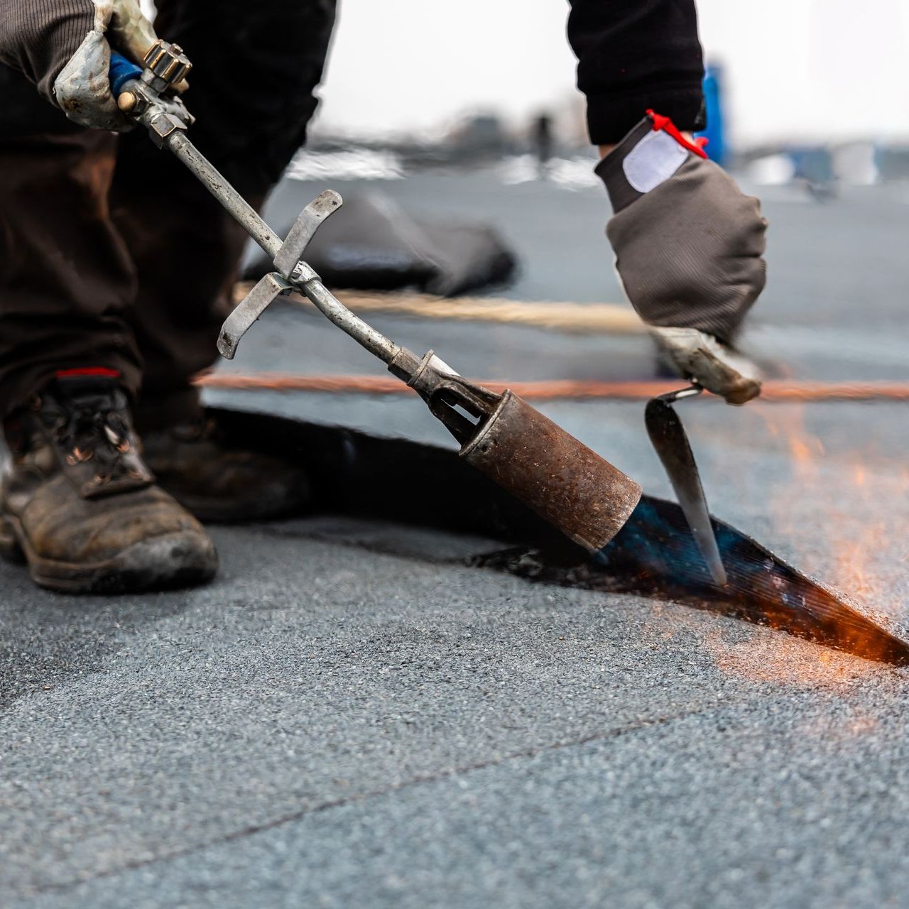 A person is using a torch on a roof.