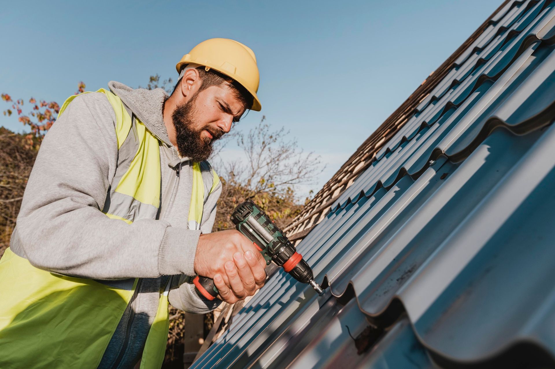 A man is working on a roof with a drill.