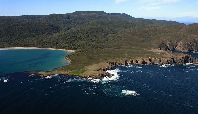 An aerial view of a small island in the middle of a large body of water surrounded by mountains.