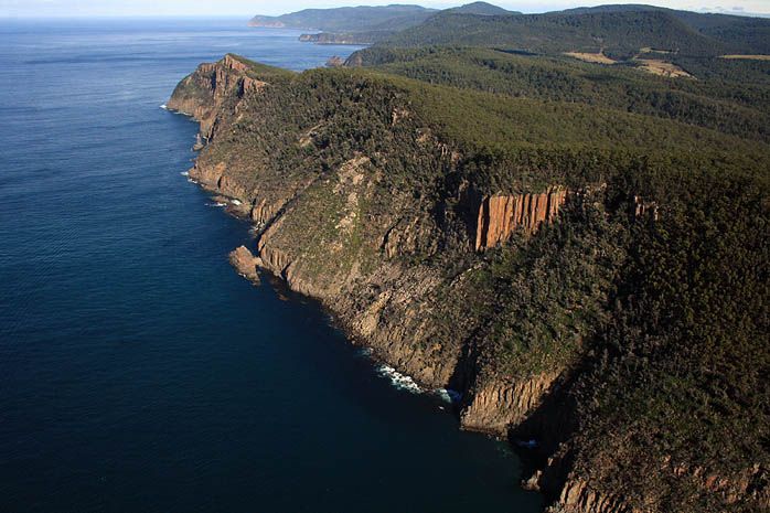 An aerial view of a cliff overlooking the ocean at sunset.