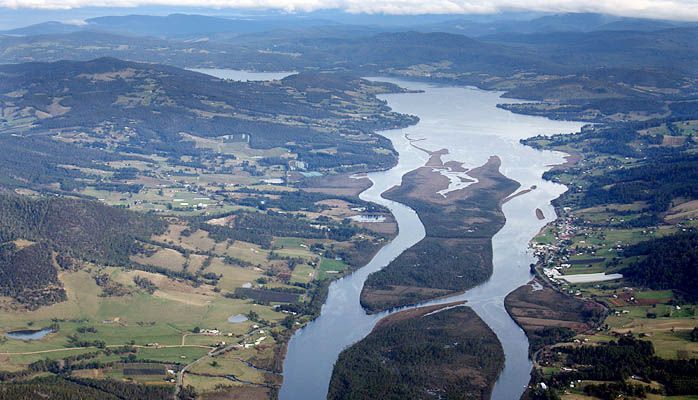 An aerial view of a river surrounded by mountains and fields
