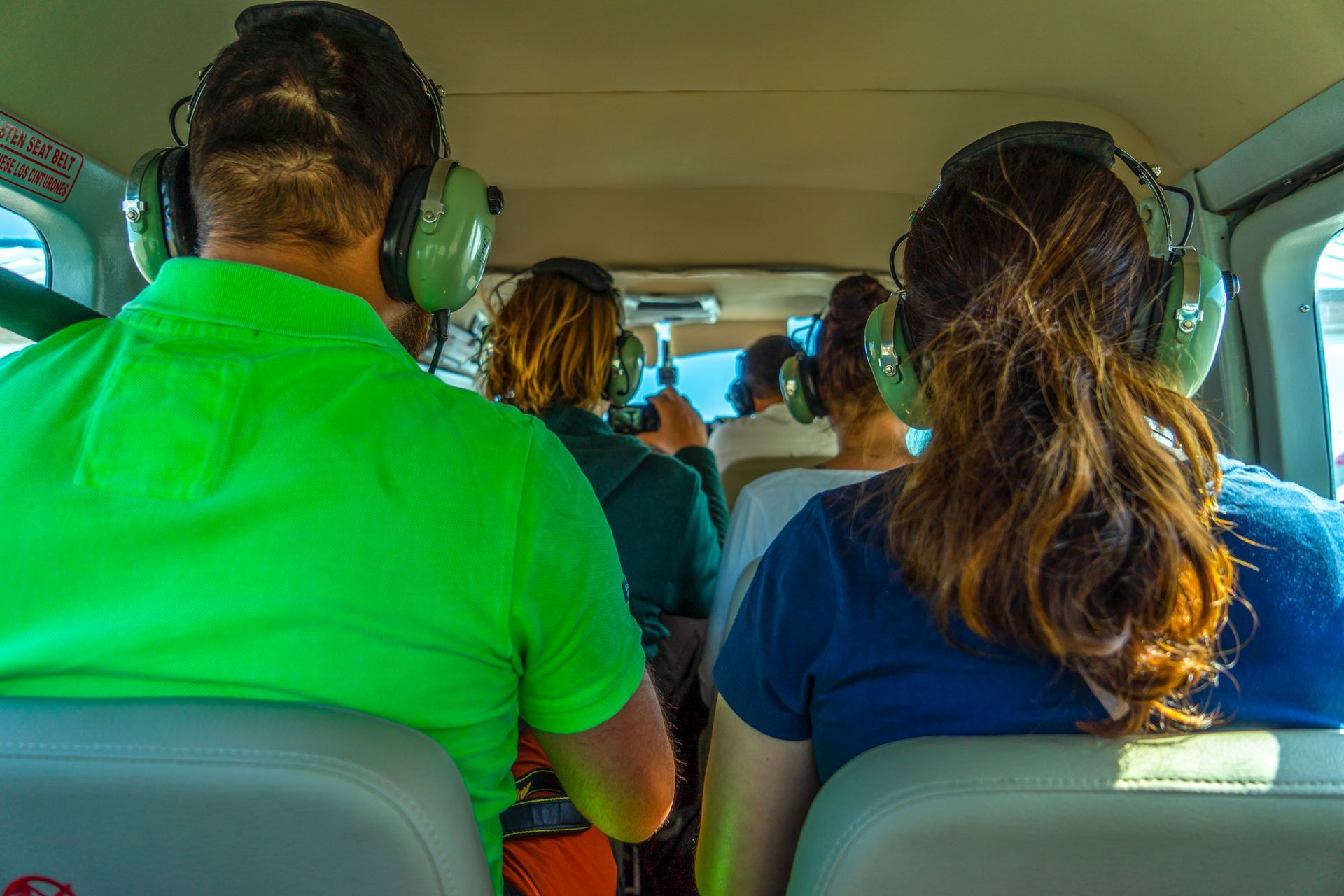 A rear view of a group of tourist passengers inside a small sightseeing plane.