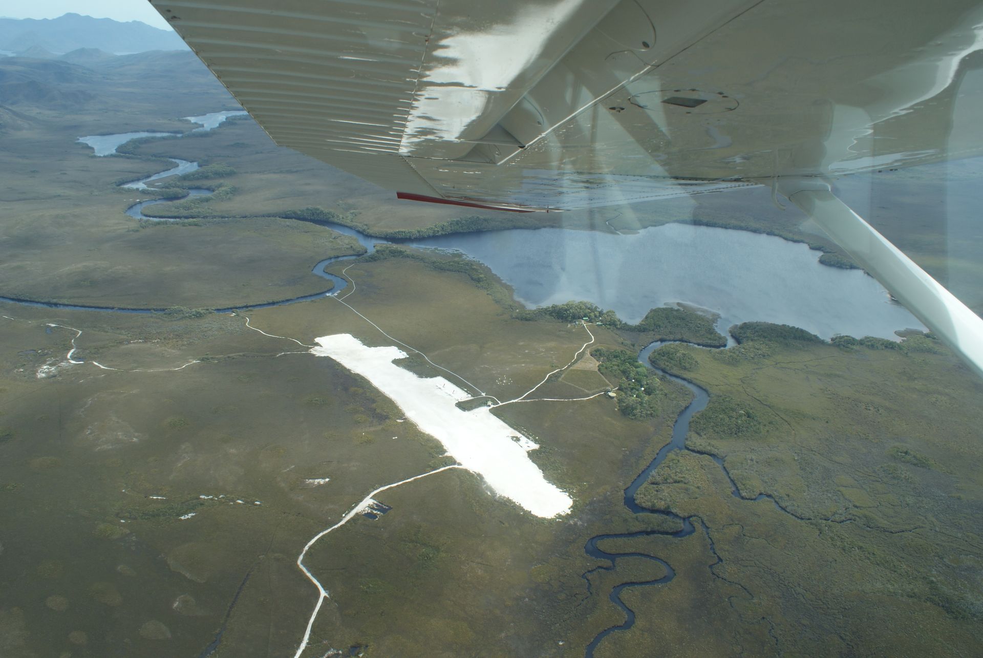 A sandy beach with a small island in the distance on a cloudy day.