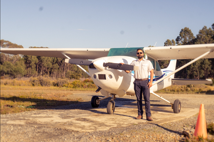 Cessna 182  with a pilot  on the side and Trees behind.