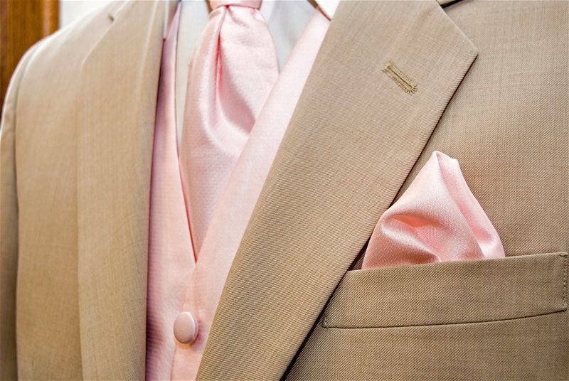 A man in a tan suit with a pink vest and tie
