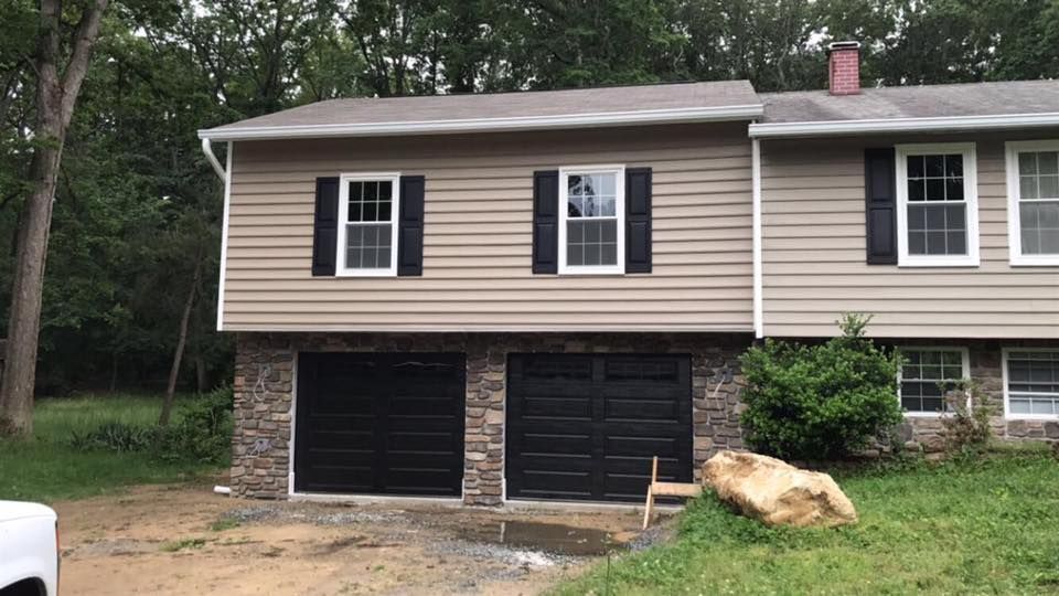 A house with a black garage door and a white truck parked in front of it.