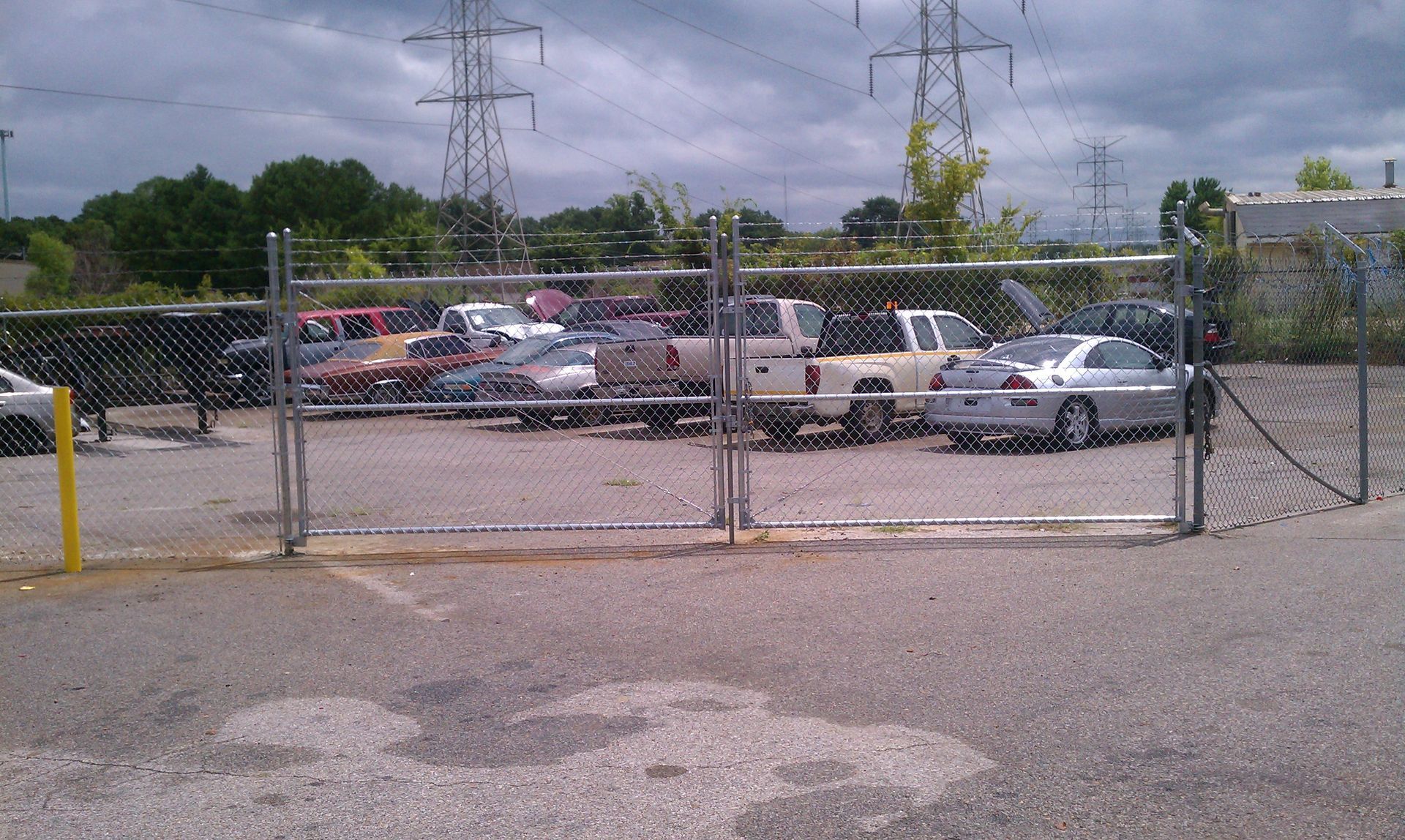 A lot of cars are parked behind a chain link fence