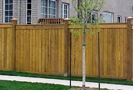 A wooden fence with a tree in front of a house.