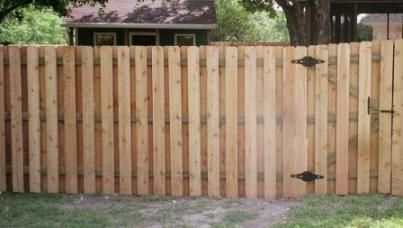 A wooden fence with a gate in front of a house.
