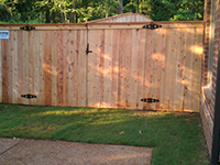 A wooden fence with a gate in the backyard of a house.