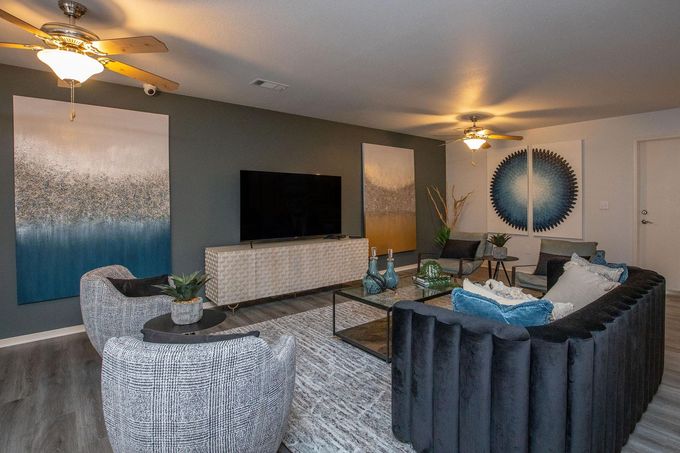 A living room with a couch , chairs , a television and a ceiling fan at Rena Valley in Van Buren, AR.