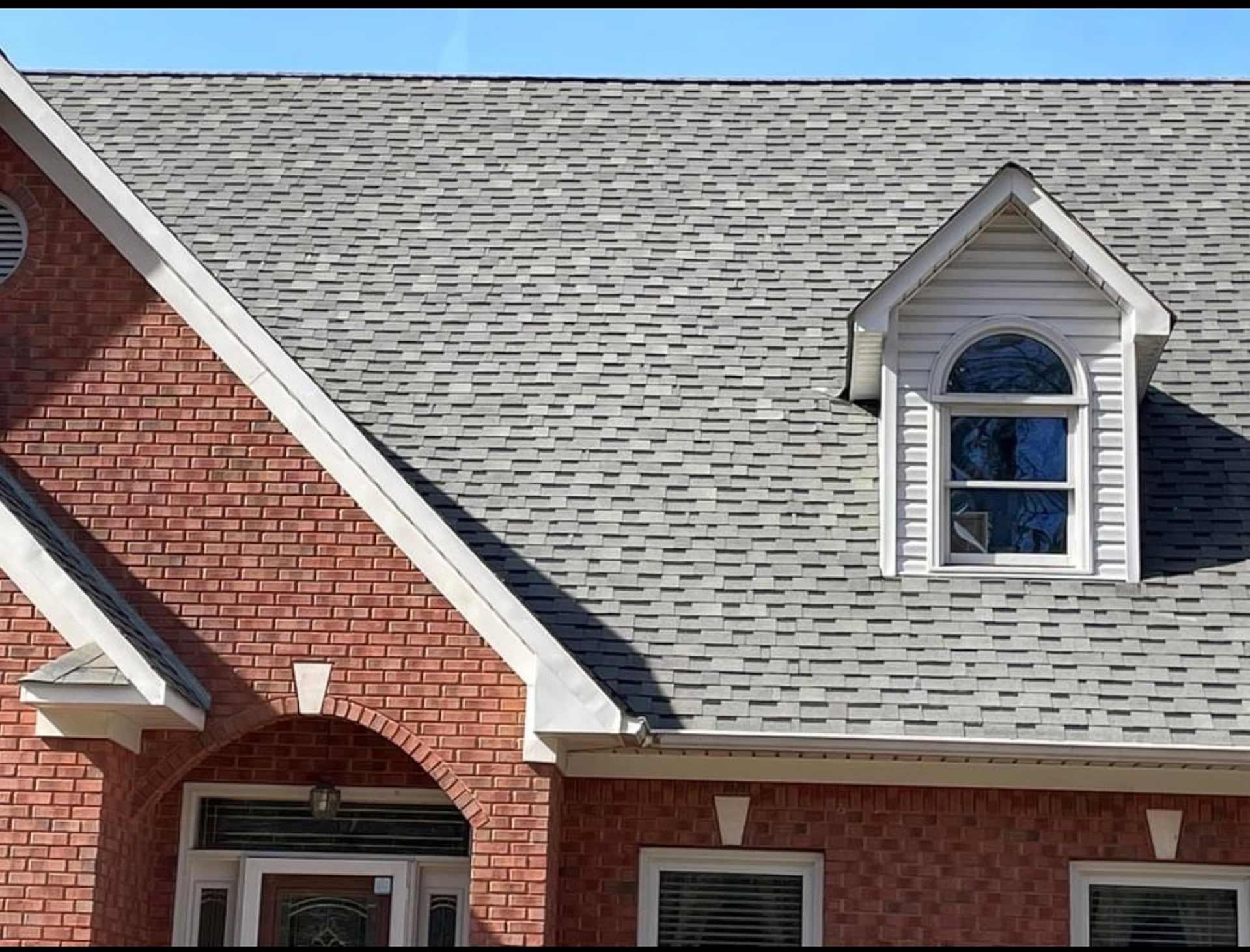 A brick house with a gray roof and a window