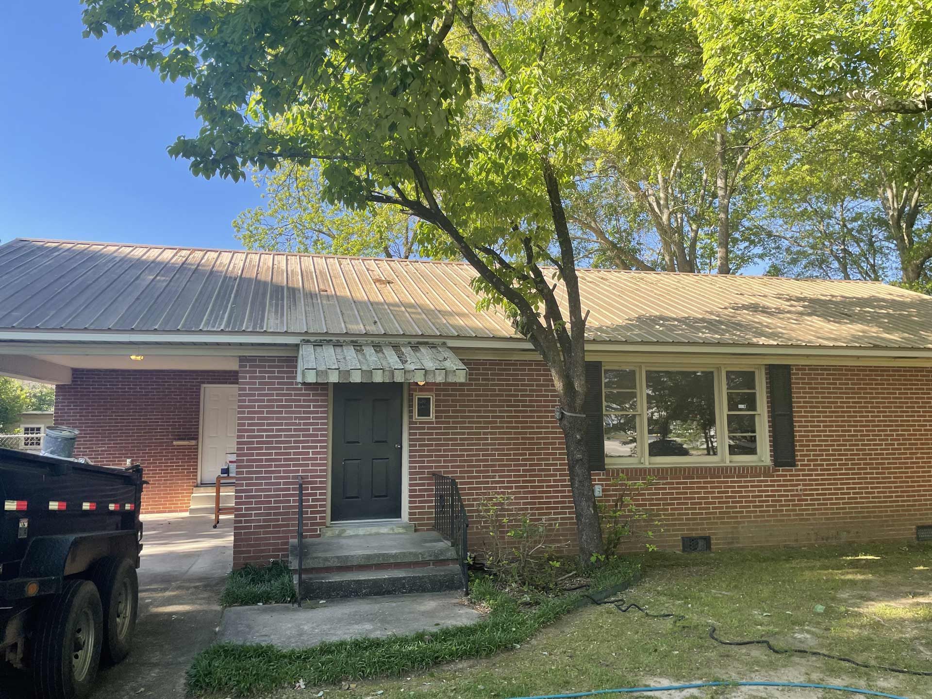 A dumpster is parked in front of a brick house