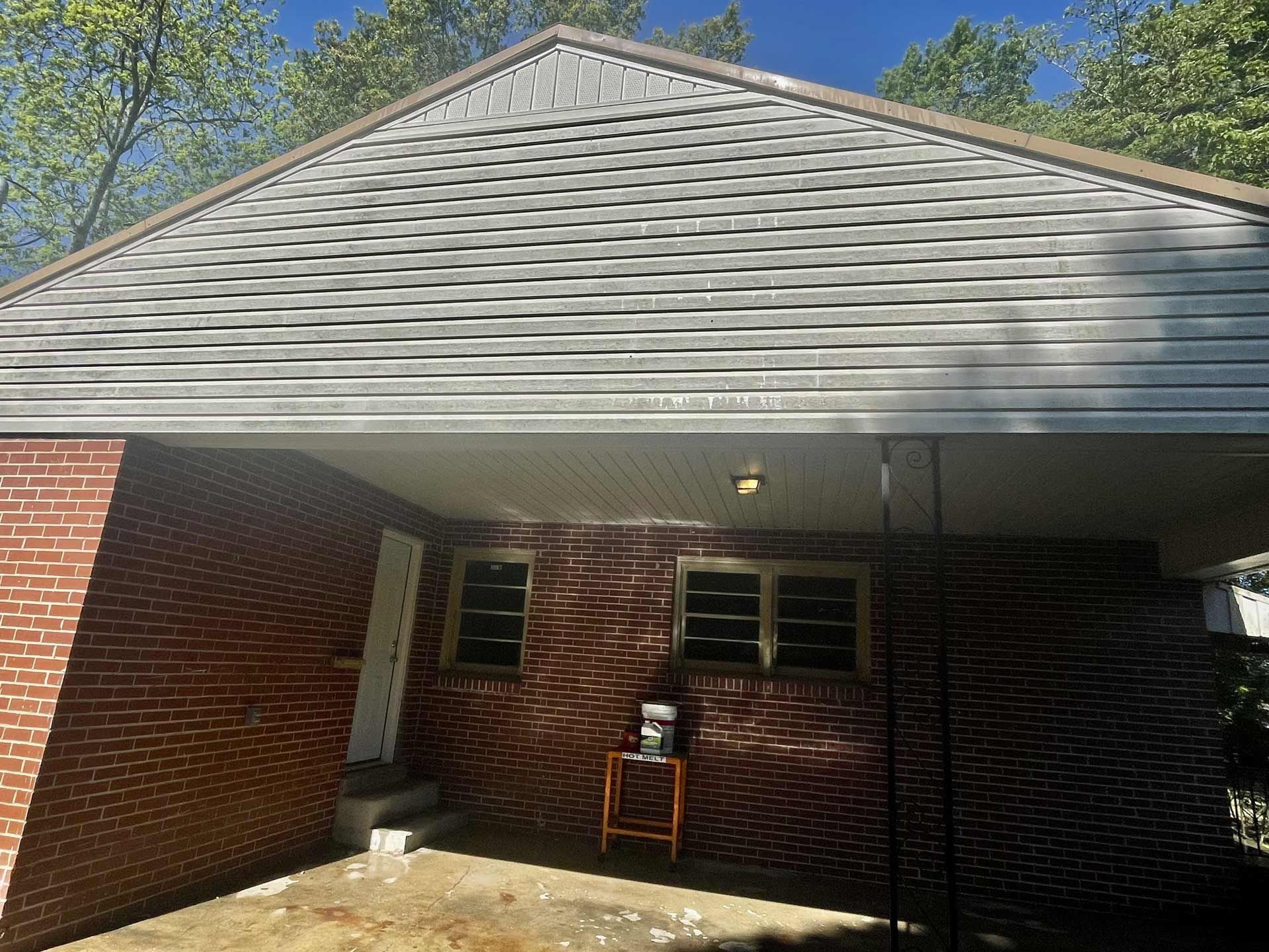 A brick house with a white roof and a covered porch