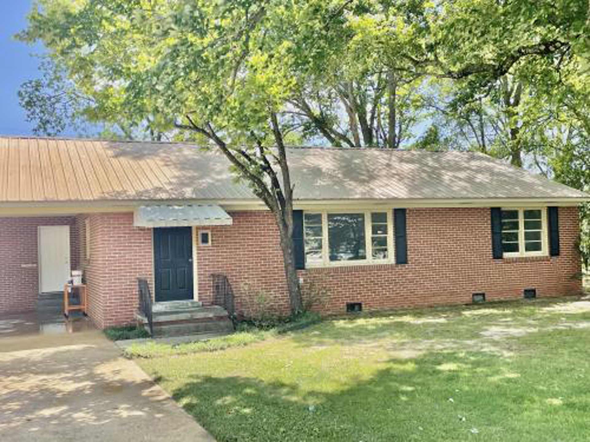 A brick house with a black door and white trim is for sale