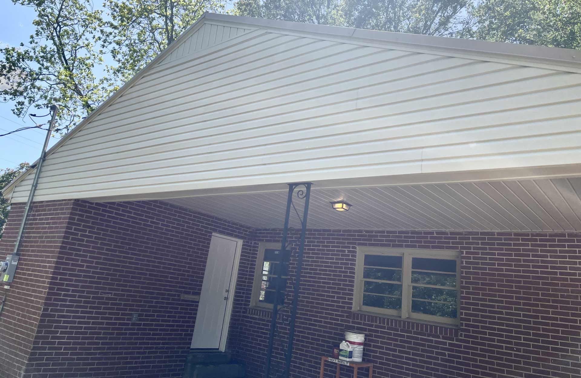 A brick house with a white siding and a porch
