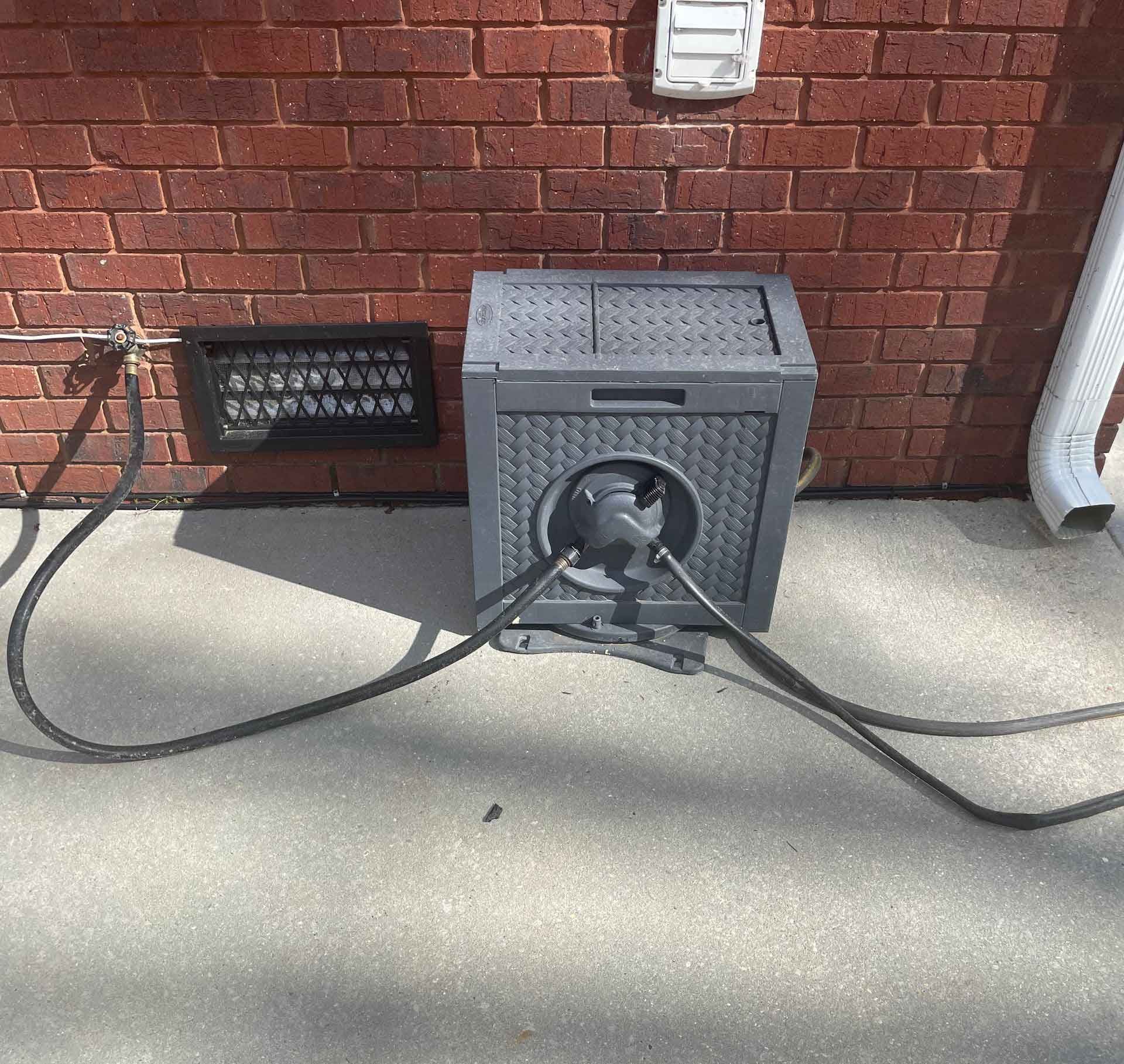 A person is using a high pressure washer to clean a wooden deck.