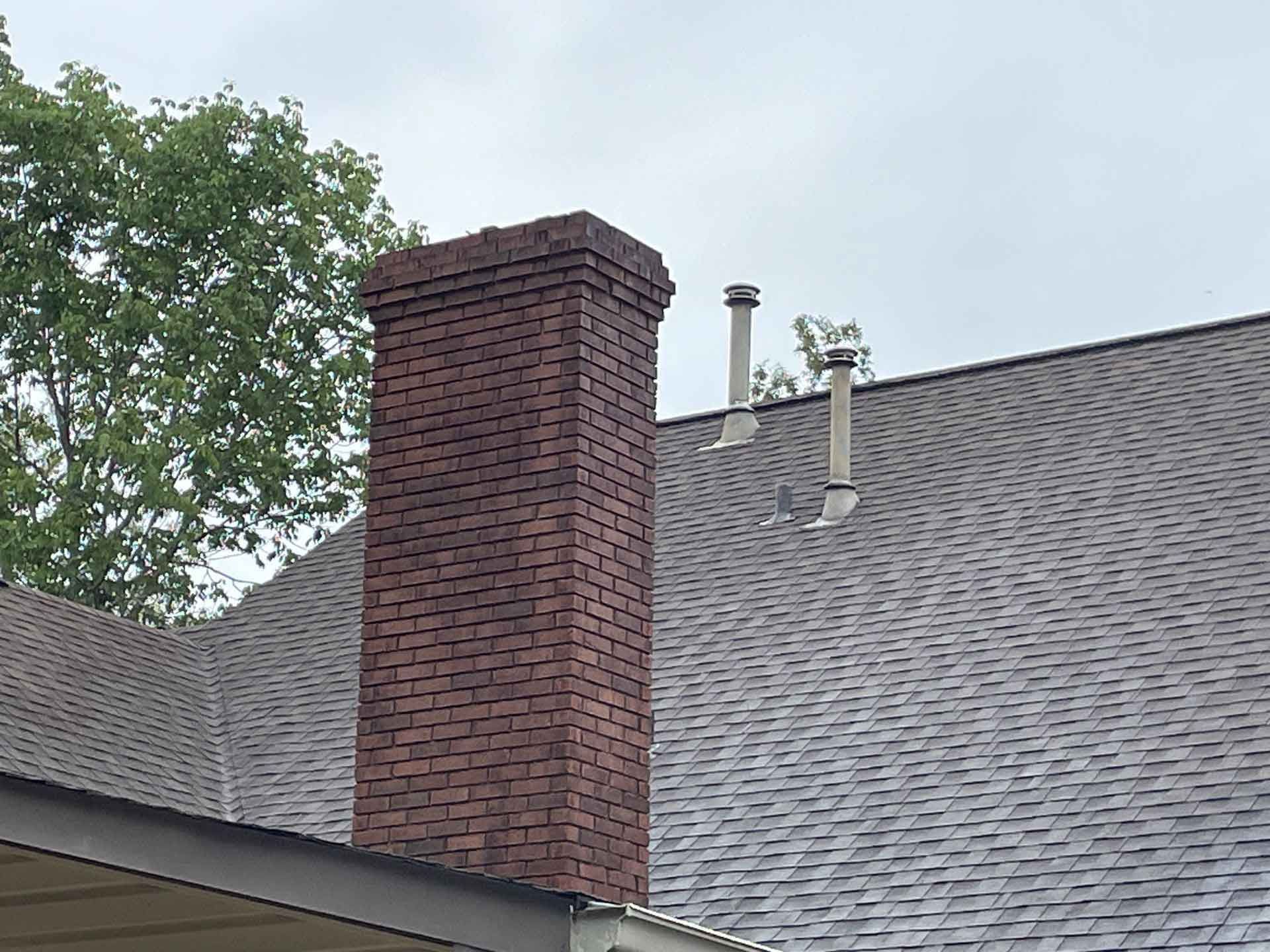 A man is cleaning the roof of a house with a high pressure washer.
