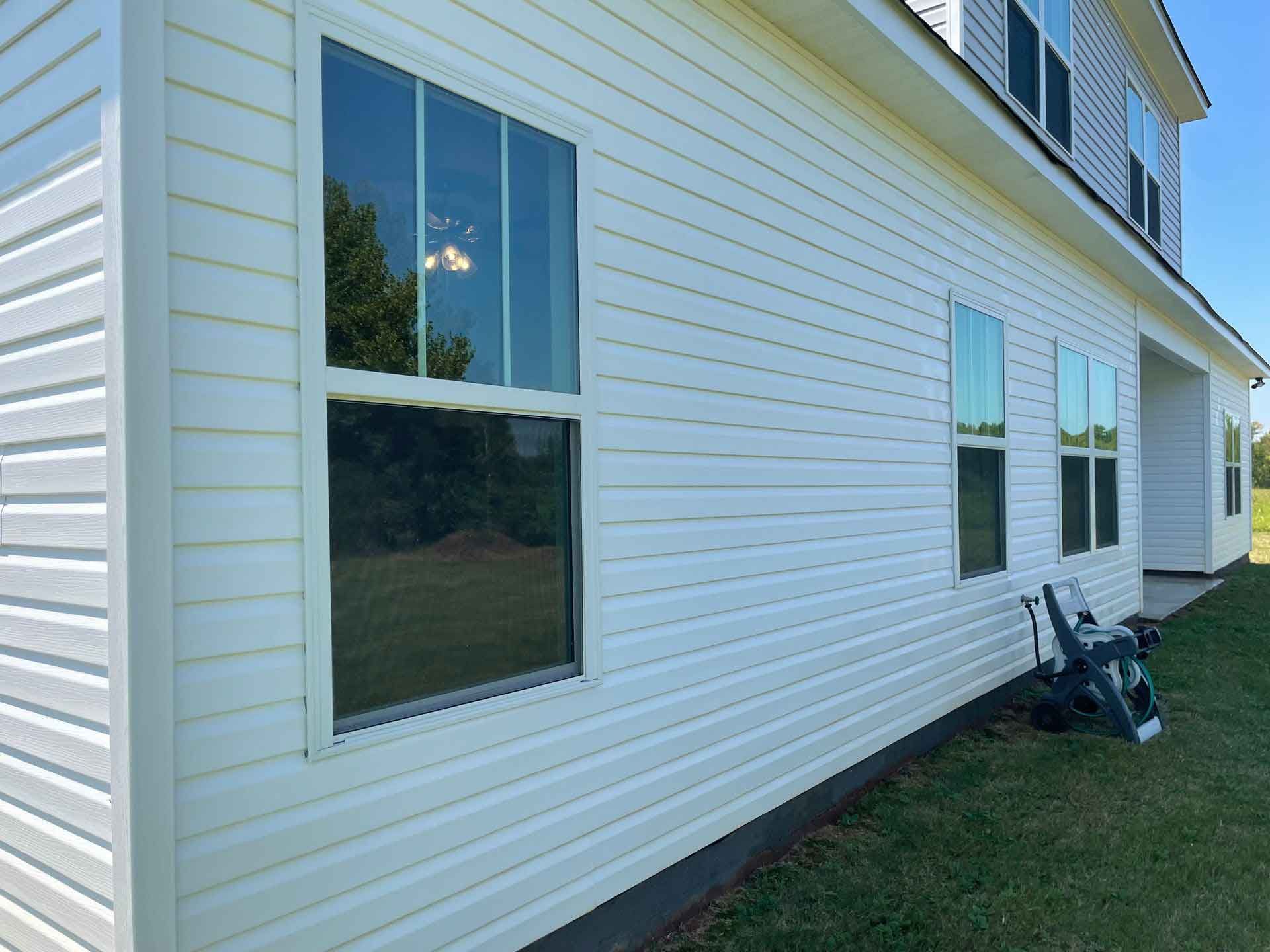 A man is standing on a ladder washing the side of a house.