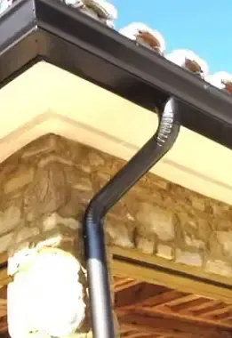 Black rain gutter on a stone building.