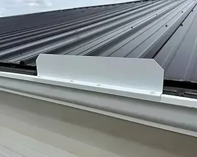 Metal roof edge flashing over a gutter, painted white.