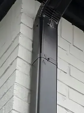 Black downspout on white brick building corner.