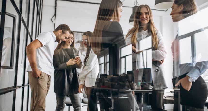 A group of people are standing around a table in an office.