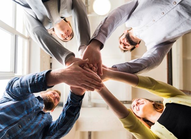 A group of people are putting their hands together in a circle.