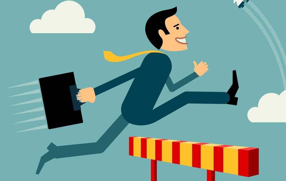 A man in a suit and tie is jumping over a hurdle while holding a briefcase.