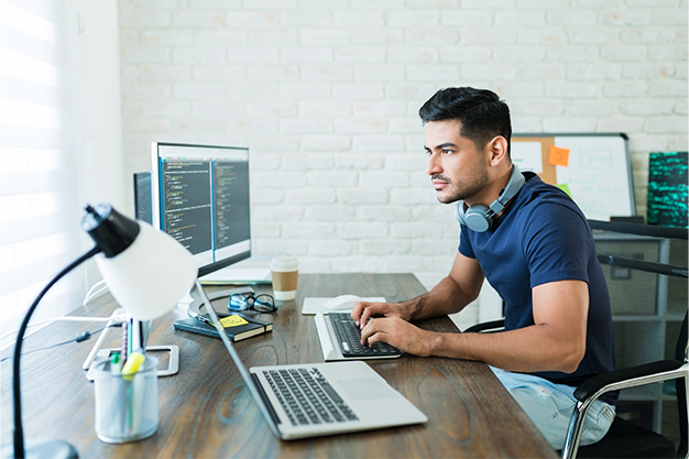 A man is sitting at a desk using a laptop computer.