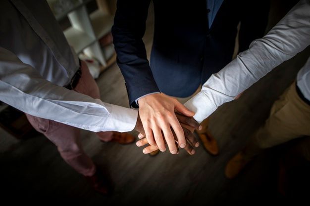 A group of people are putting their hands together in a circle.