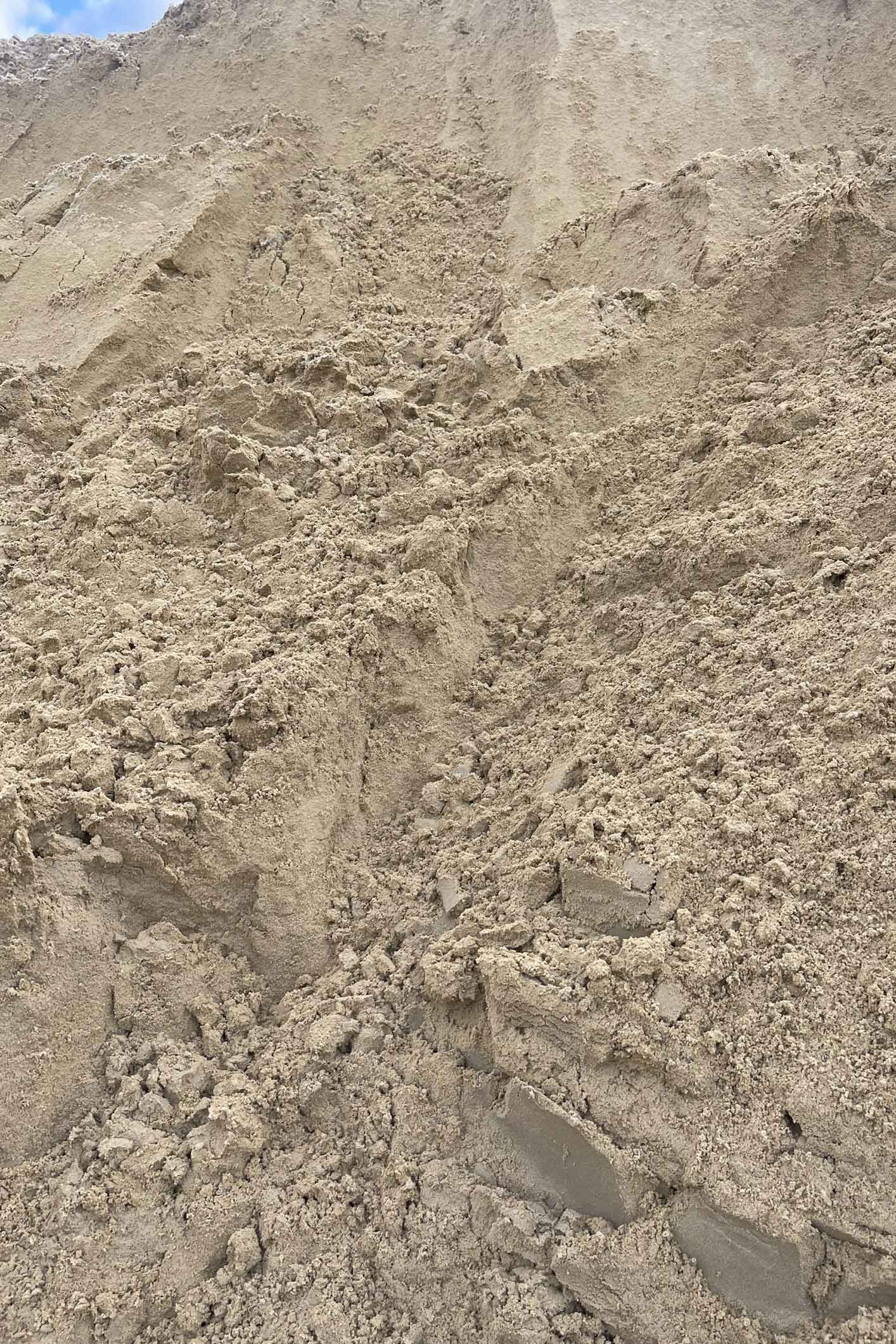 A pile of sand is sitting on top of a pile of dirt.