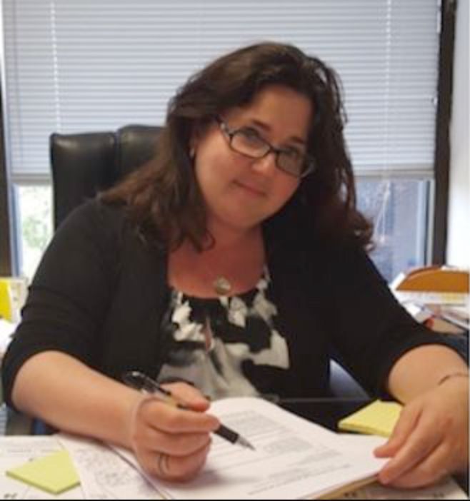 A woman is sitting at a desk with a pen in her hand