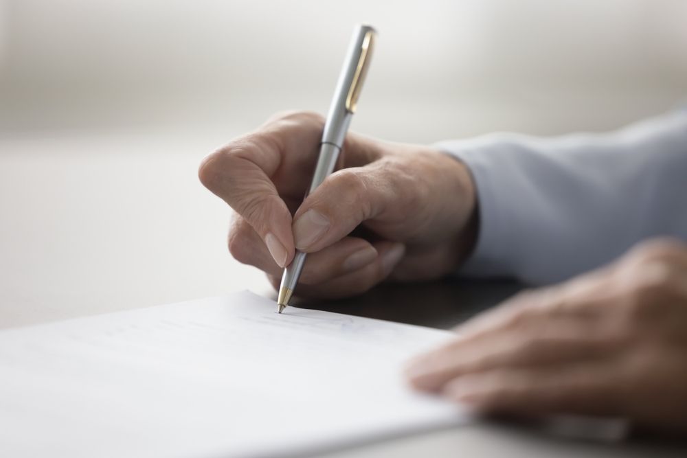 A person is writing on a piece of paper with a pen.
