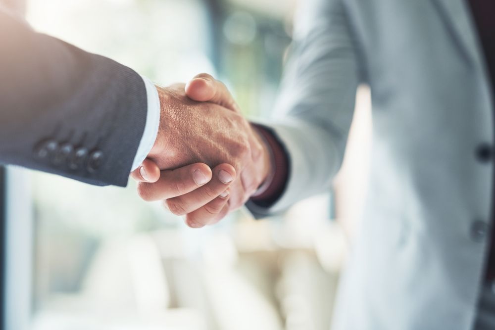 Two businessmen are shaking hands in an office.