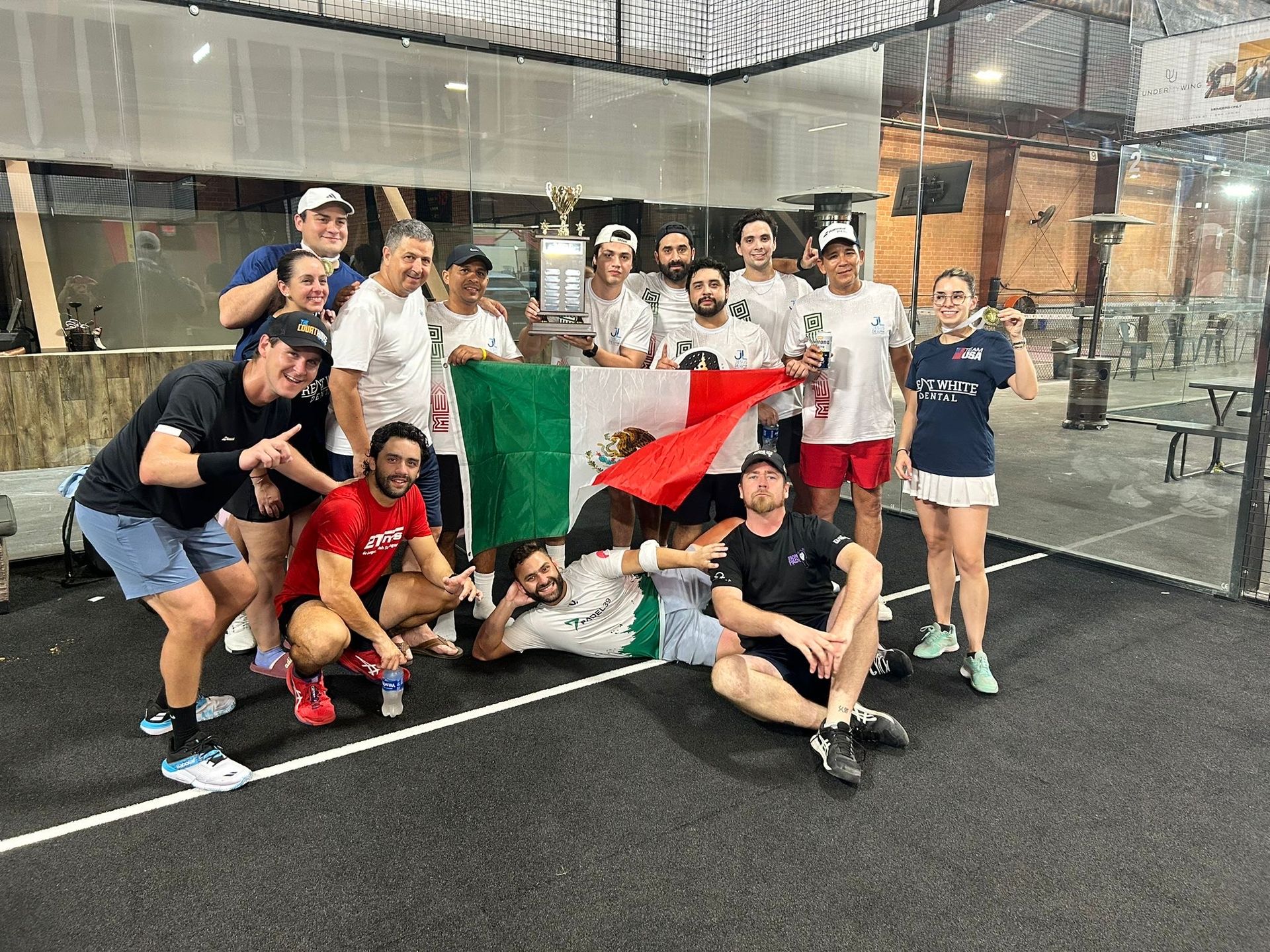 A man is playing tennis on a court with a brick wall in the background.
