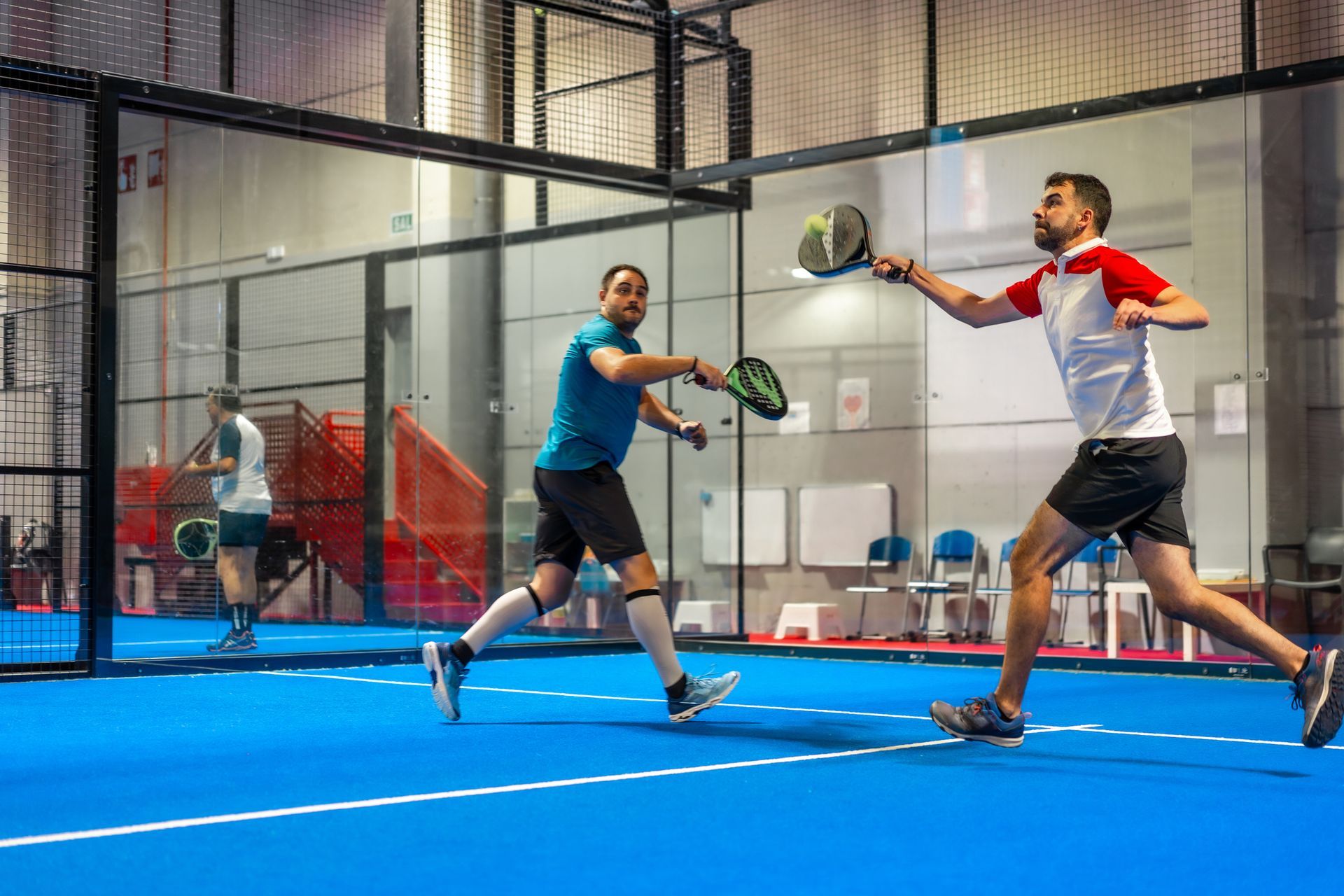 Two men are playing indoor padel.