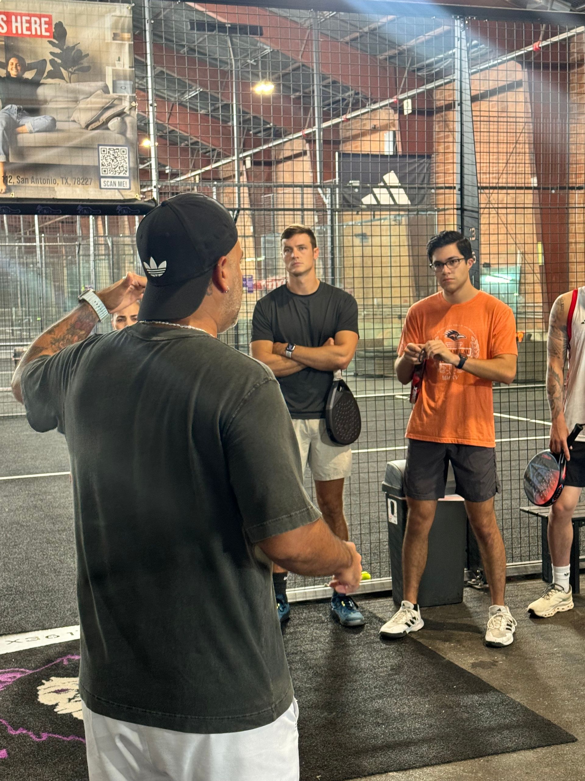 A group of young women are standing on a tennis court holding tennis rackets.
