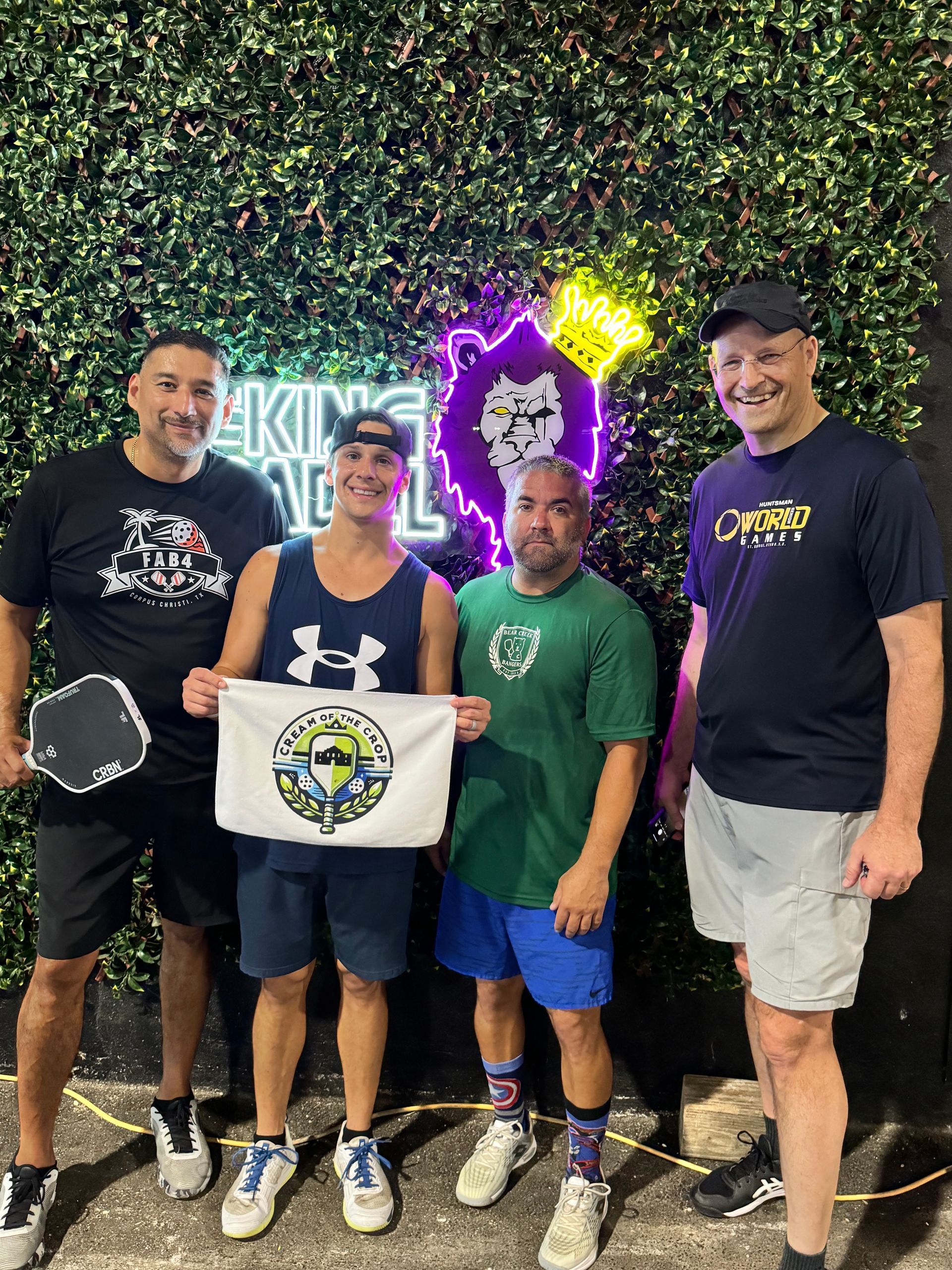 A group of men are standing next to each other on a tennis court holding certificates.