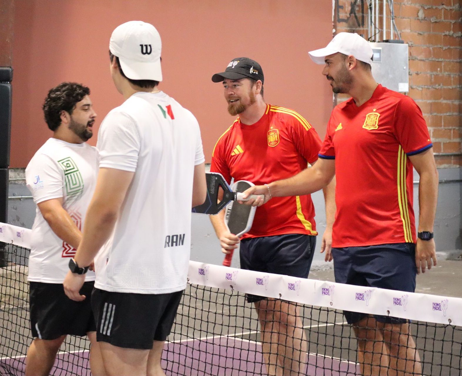 A man is holding a paddle tennis racquet on a court.
