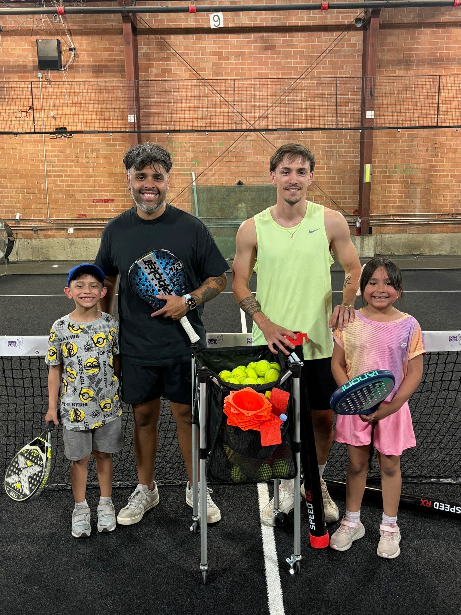 Two women are holding tennis rackets in their hands in a gym.