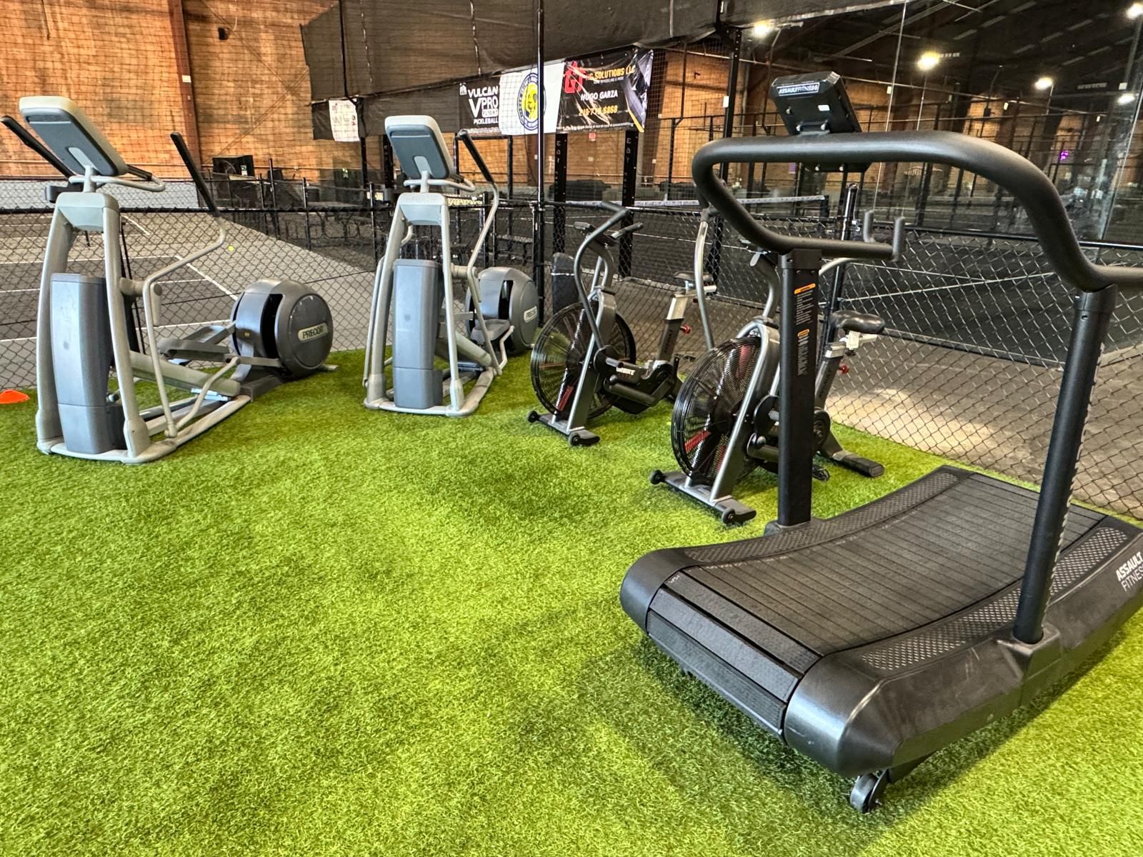 A man in a black shirt is squatting down while holding a barbell over his head
