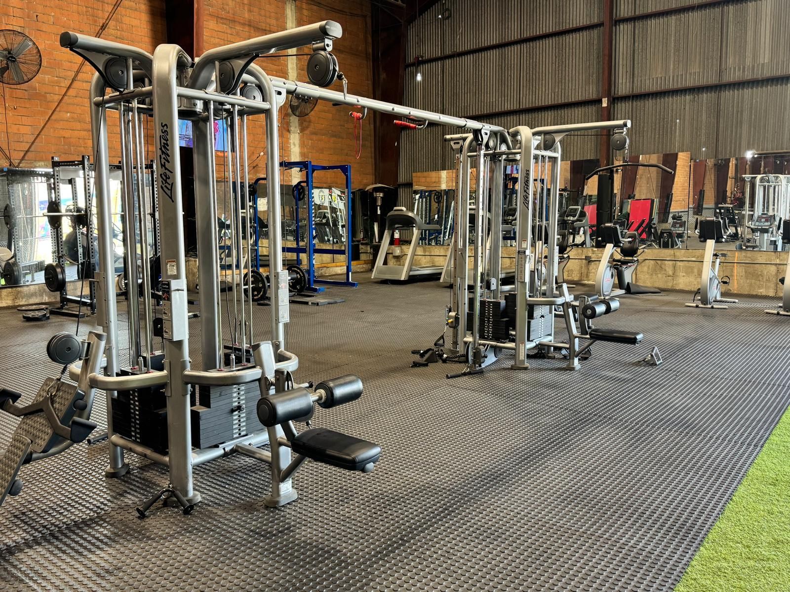 Two women are squatting with a barbell in a gym