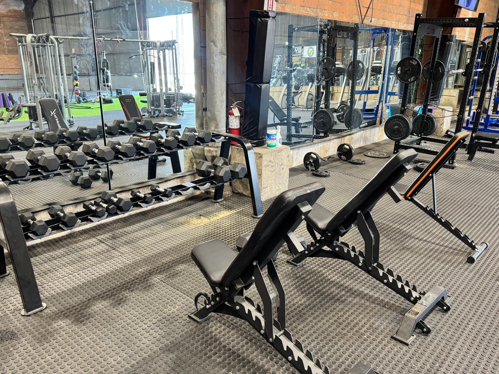A woman is holding a kettlebell over her shoulder in a gym.