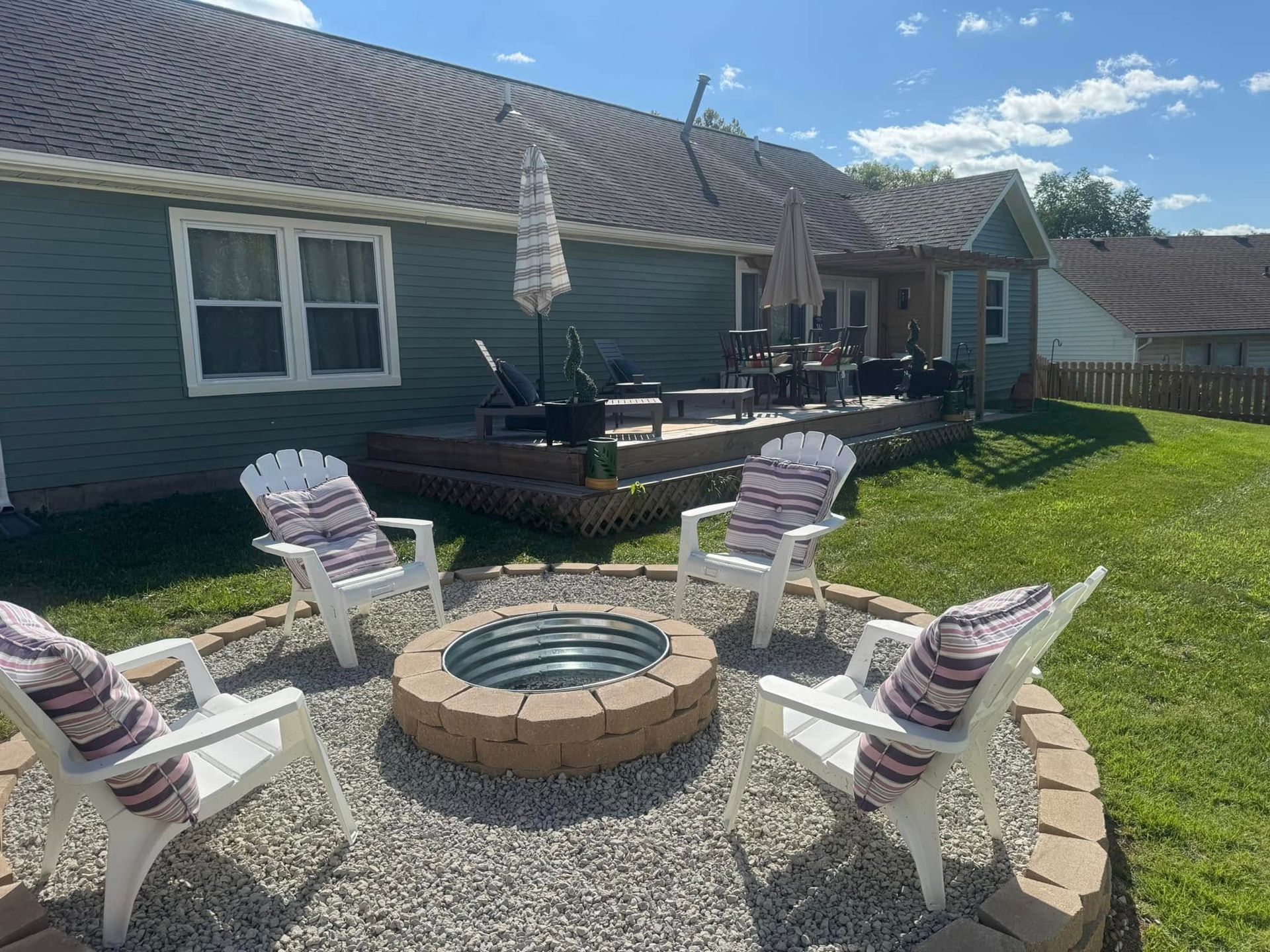 A fire pit with chairs around it in front of a house.