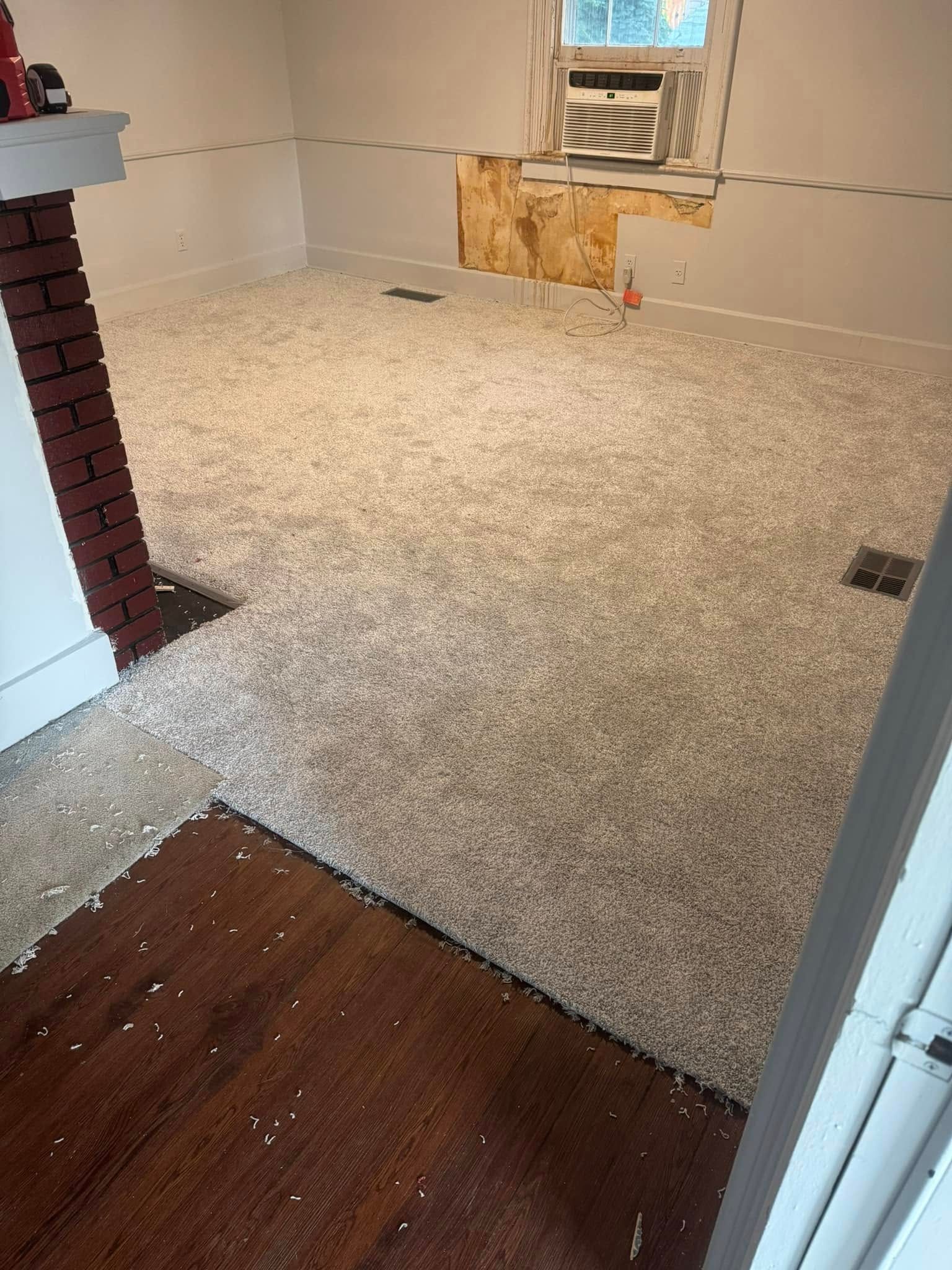 A room with a lot of carpet on the floor and a brick fireplace.