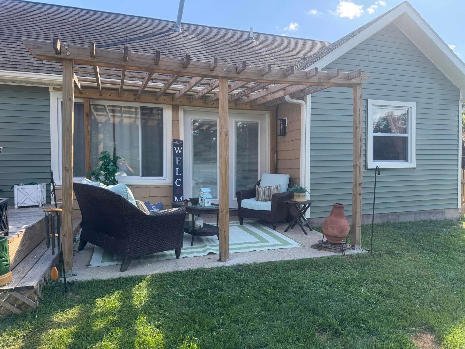 A house with a pergola and patio furniture in front of it.